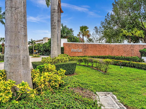 View of a landscaped entrance area with a red brick wall displaying the name 'Point East'.