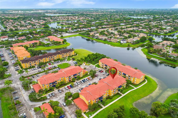 Aerial view of apartment buildings with red roofs, surrounded by lakes and a network of roads in a suburban area.