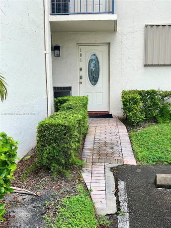 Front view of an entrance to a building unit with a white door and small pathway.