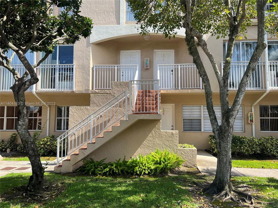 Front view of a multi-story residential building with exterior stairs and balconies.