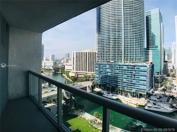 View from a balcony overlooking a city skyline with modern high-rise buildings and a waterway.