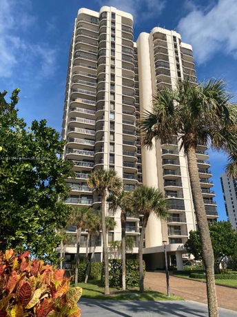 Front view of a tall residential building with multiple balconies.