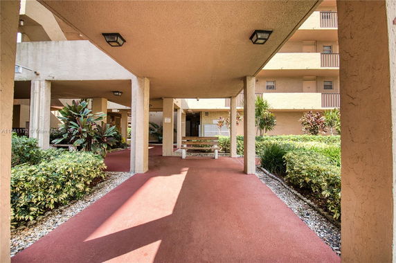 Entrance area with covered walkways and greenery.