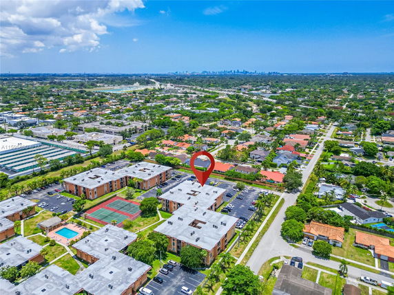 Aerial view of a residential area with multiple apartment buildings, a swimming pool, and tennis courts.