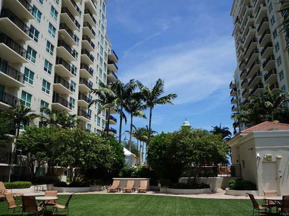 View between two high-rise apartment buildings with a landscaped garden and patio chairs.
