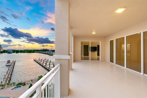 Covered balcony with sliding glass doors overlooking a waterfront view.