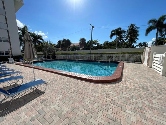 Outdoor swimming pool area with loungers and umbrellas.