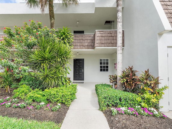 Front view of a two-story building with a walkway and landscaped garden.