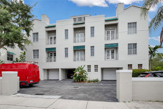 Front view of a multi-story building with garages and balconies.