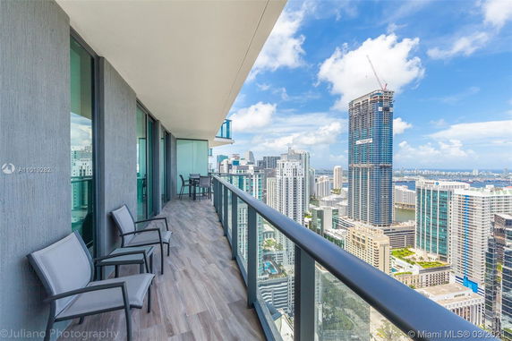 View from a balcony overlooking a cityscape with tall buildings and a clear blue sky.