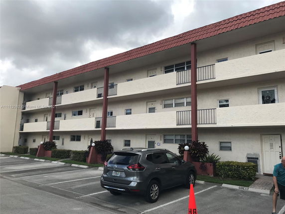 Front view of a multi-story residential building with balconies and a tiled roof.