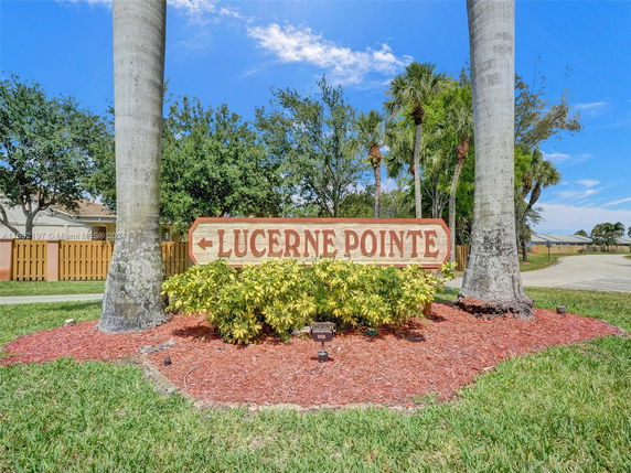Signage of Lucerne Pointe surrounded by palm trees and manicured landscaping.