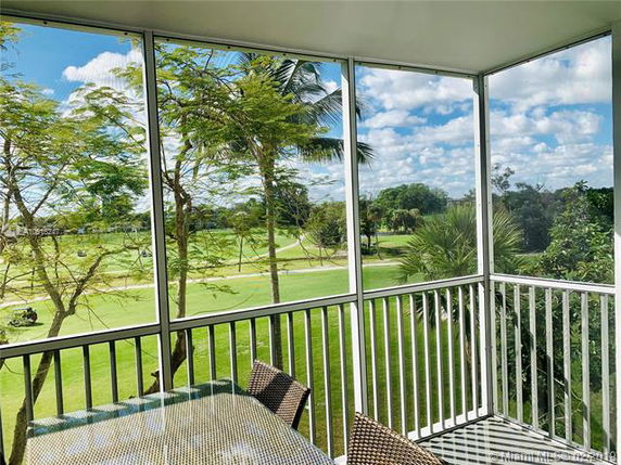 View of surrounding greenery and palm trees from a screened balcony.
