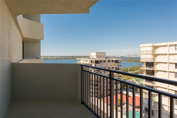 View from a balcony overlooking other buildings and a body of water.