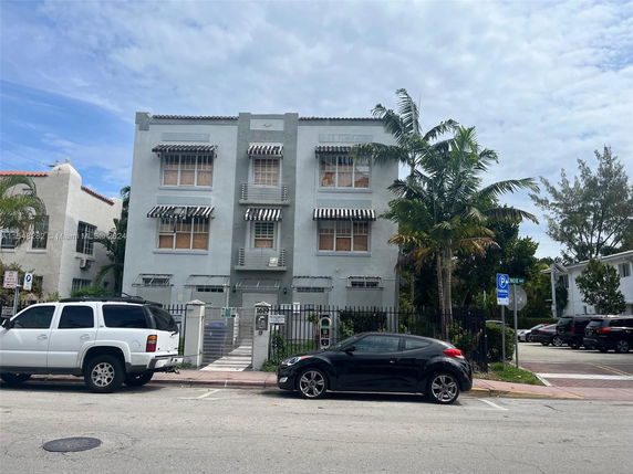 Front view of a three-story residential building with striped awnings.
