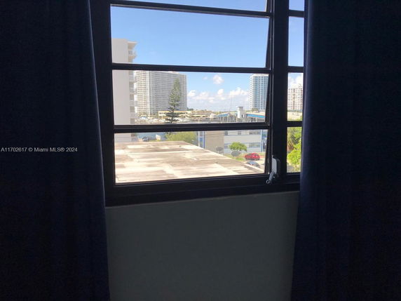 View from a window showing buildings and a clear sky.