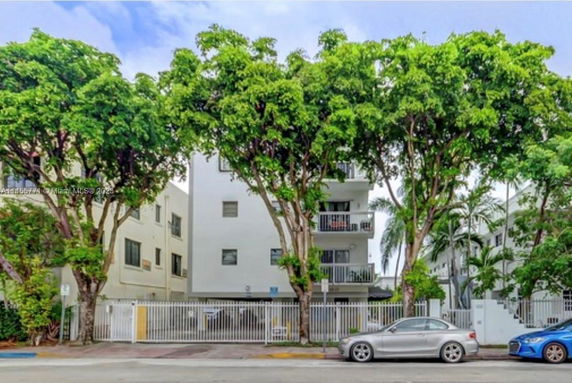 Front view of a multi-story residential building with balconies and a gated entrance.