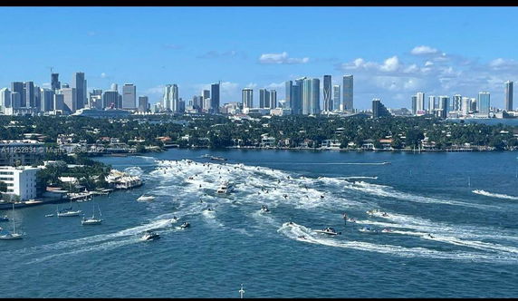 Panoramic city view with waterfront and boats in the foreground.