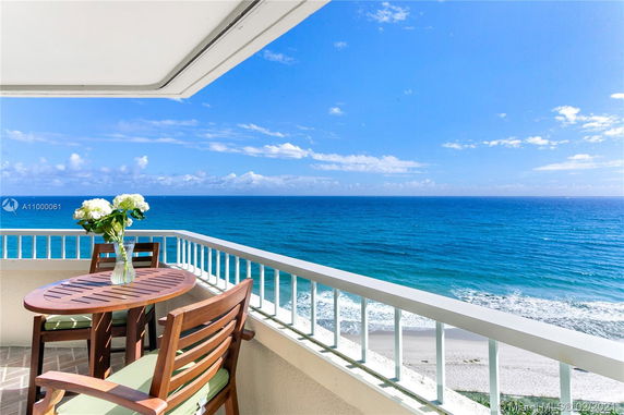 Ocean view from a balcony with a table and chairs.