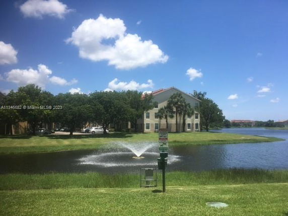 Front view of a multi-story building with a pond and fountain in front.