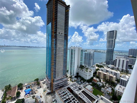 View of high-rise buildings next to a body of water with a partially cloudy sky.