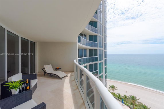 View from a high-rise balcony overlooking the ocean and beach.
