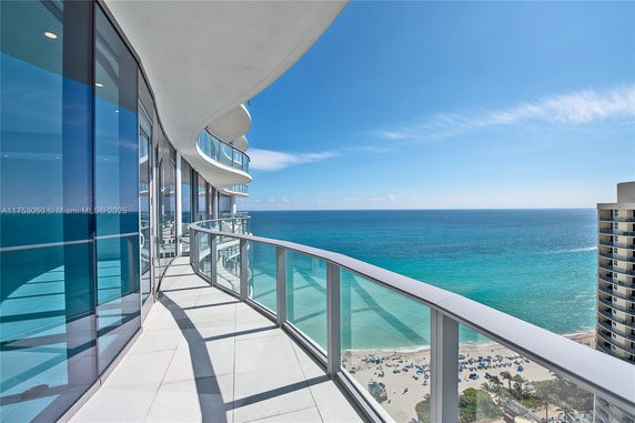 Panoramic view from a curved balcony overlooking the ocean and beach.