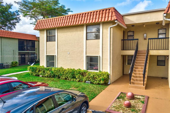 Front view of a two-story apartment building with stair access and red tile roofing.