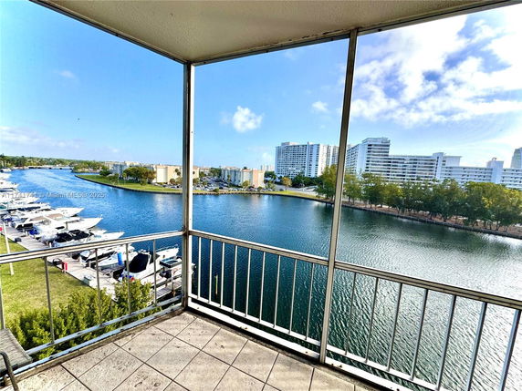 View from a balcony overlooking a marina and waterfront buildings.