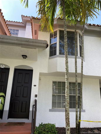 Front view of a two-story house with black door and bay windows.