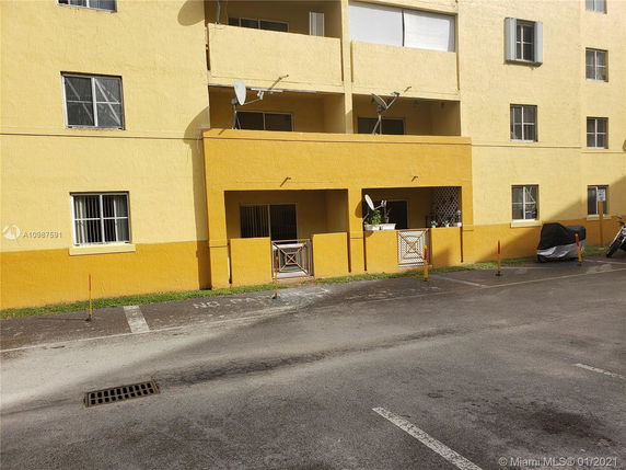 Front view of a multi-story yellow building with balconies and multiple windows.