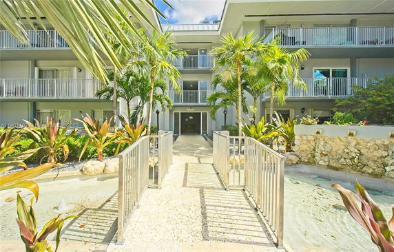 Front view of a multi-story building with balconies and surrounding greenery.