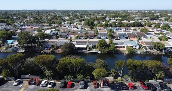 Aerial view of residential neighborhood with a waterway and parking area visible.