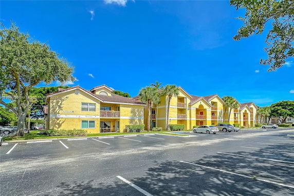 Front view of a multi-story apartment building with yellow walls and brown roofs.