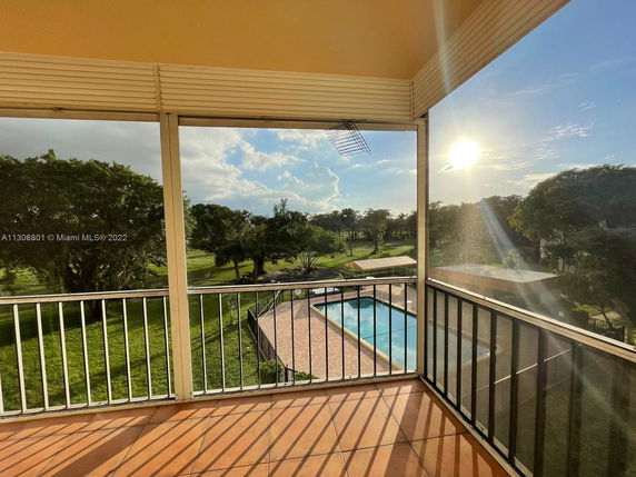 View from a balcony showing expansive greenery and a swimming pool.