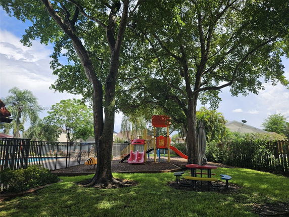 Outdoor play area with playground equipment and trees.