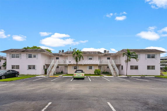 Front view of a two-story residential building with external staircases and parking area.