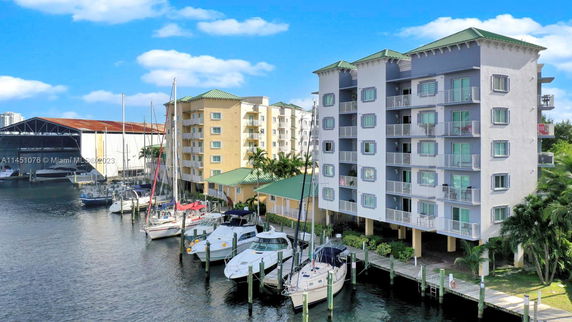 Front view of multi-story waterfront apartment buildings with balconies, adjacent to a marina with boats.