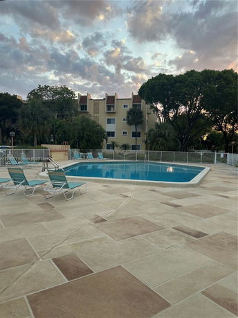 Outdoor swimming pool area with lounge chairs and surrounding fence.