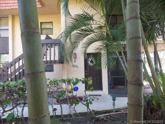 Front view of a multi-story building with stairs and tropical plants.