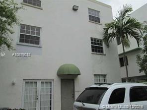 Front view of a three-story building with a green awning and multiple windows.