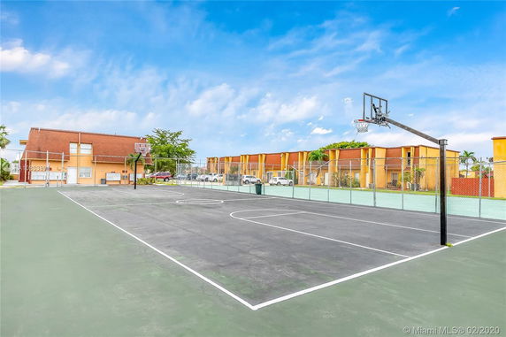 Basketball court with fencing and a row of residential buildings in the background.