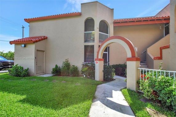 Front view of a two-story building with a red-tiled roof and arched entrance.