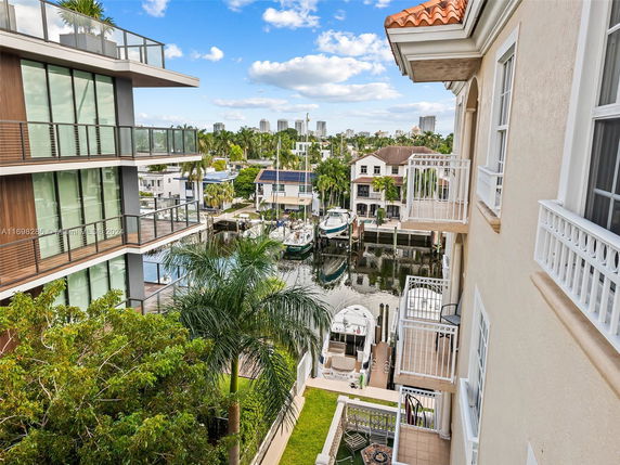 View from a building showing nearby modern buildings, balconies, and a waterway with boats.