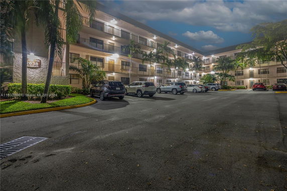 Front view of a multi-story apartment building with parking area in front.