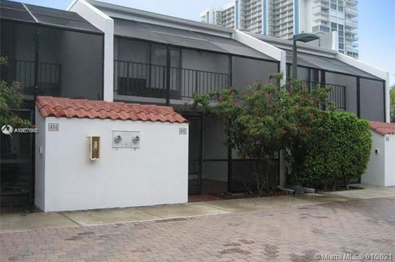 Front view of a two-story building with screened balconies and a red-tiled roof.