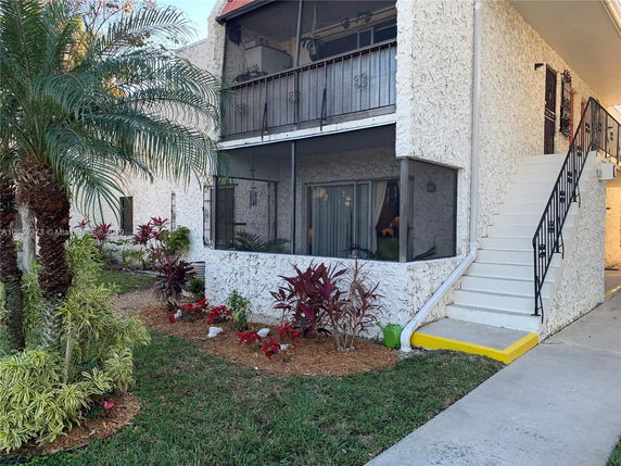 Front view of a two-story building with exterior stairs and a landscaped garden.