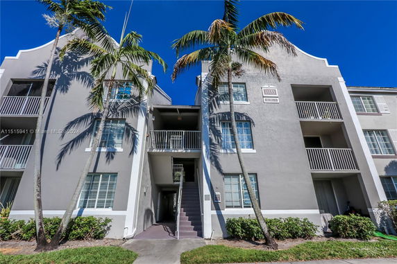 Front view of a multi-story apartment building with balconies and stairs.