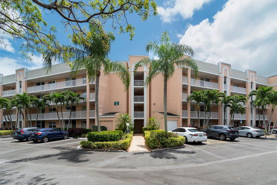 Front view of a multi-story residential building with balconies and parking area.