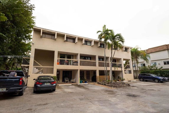 Front view of a three-story apartment building with balconies and parking area.